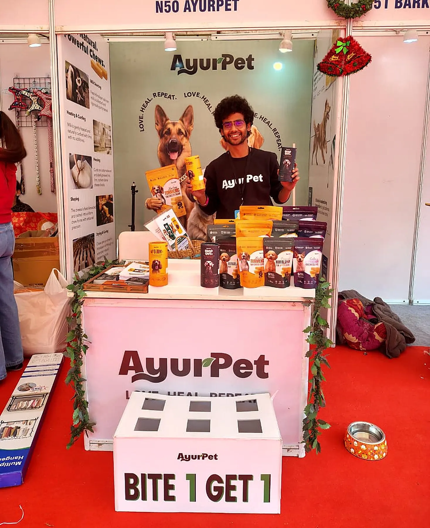 A pet expo stand displaying yak chews and pet supplements, with a team member behind the counter