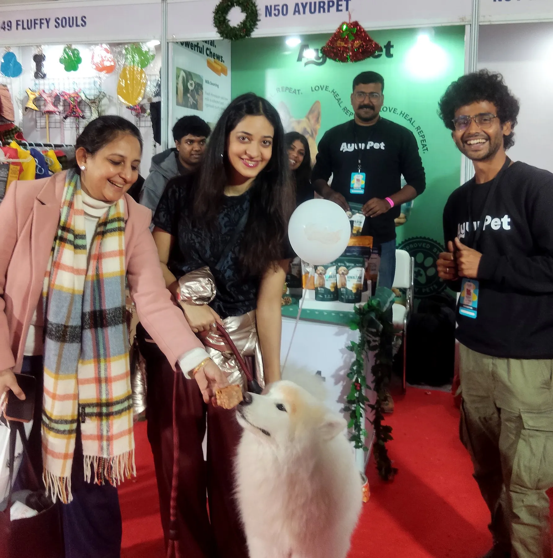 Visitors greeting a white Samoyed at a pet expo stand in India