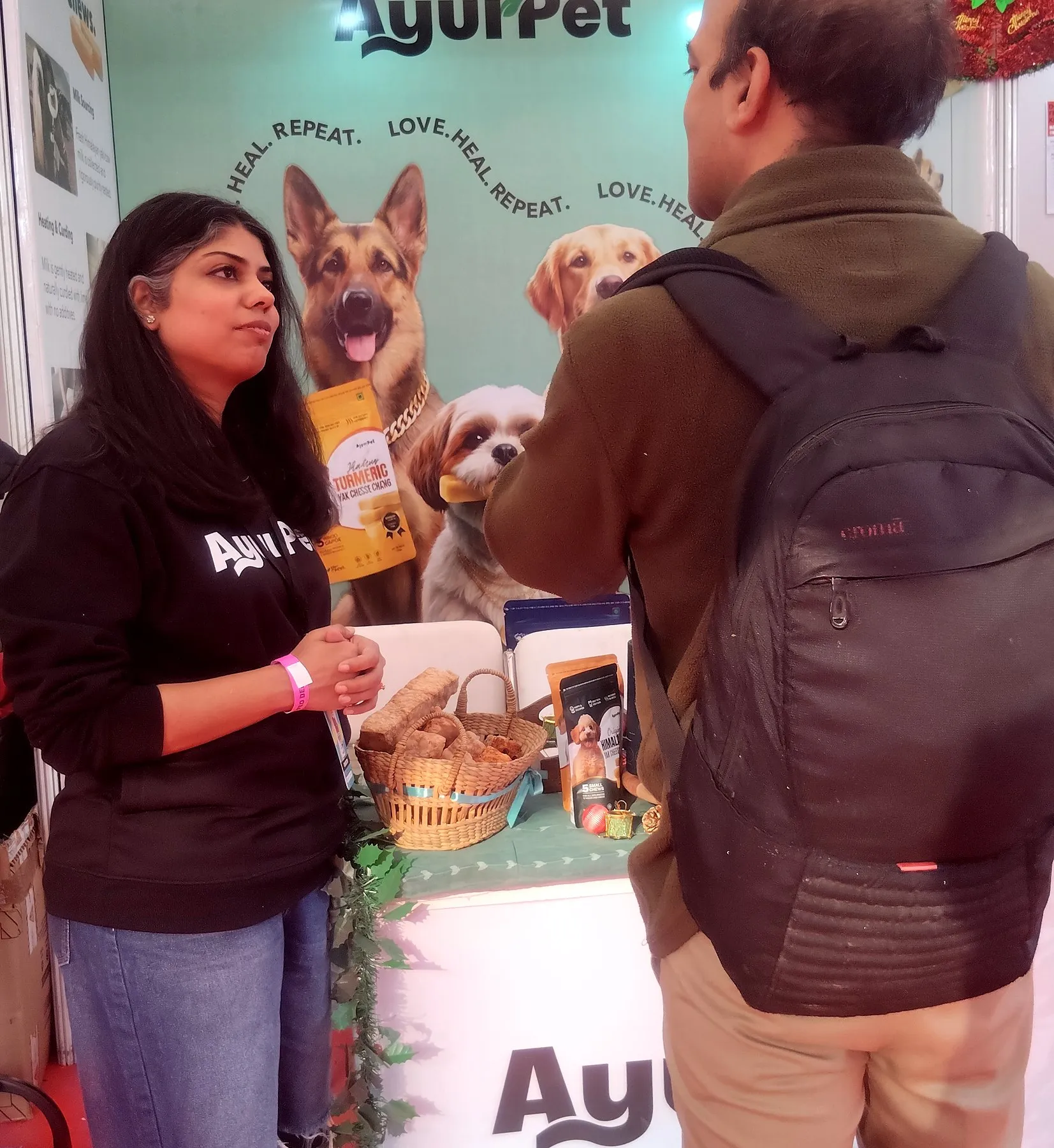 A team member explaining yak cheese chews to a visitor at a pet expo stand
